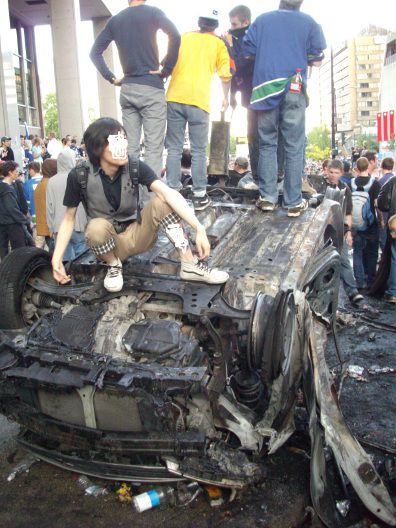 Canucks fans pose on overturned burned out car