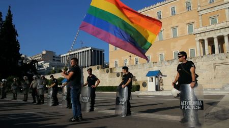 A defiant marcher waves the Pride flag in front of the Greek Parliament