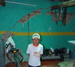 Child in front of cracked infrastructure to house.  His family claims the cracks were caused by blasts from the mine.  